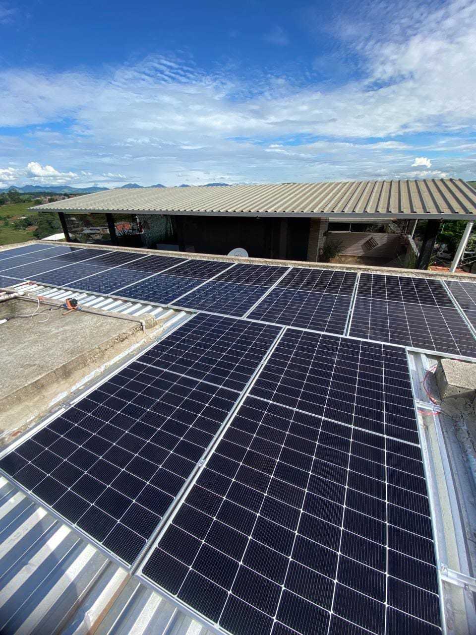 Módulos solares instalados sobre laje e telhado metálico